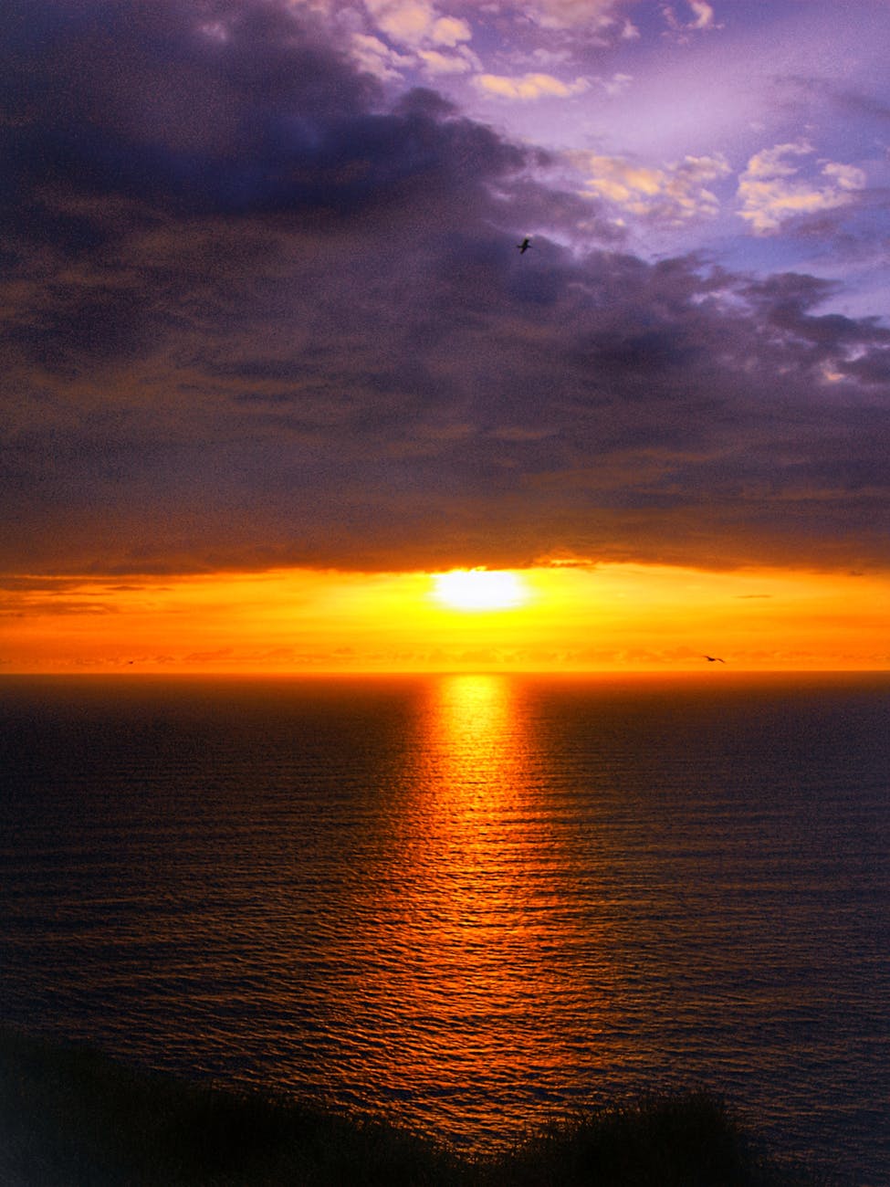 sun setting on horizon above sea