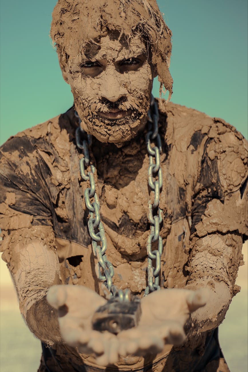 man with chain on neck covered with clay
